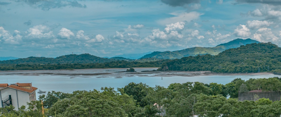 Cerros boscosos al otro lado de la entrada del Canal, con la orilla en bajamar y un islote