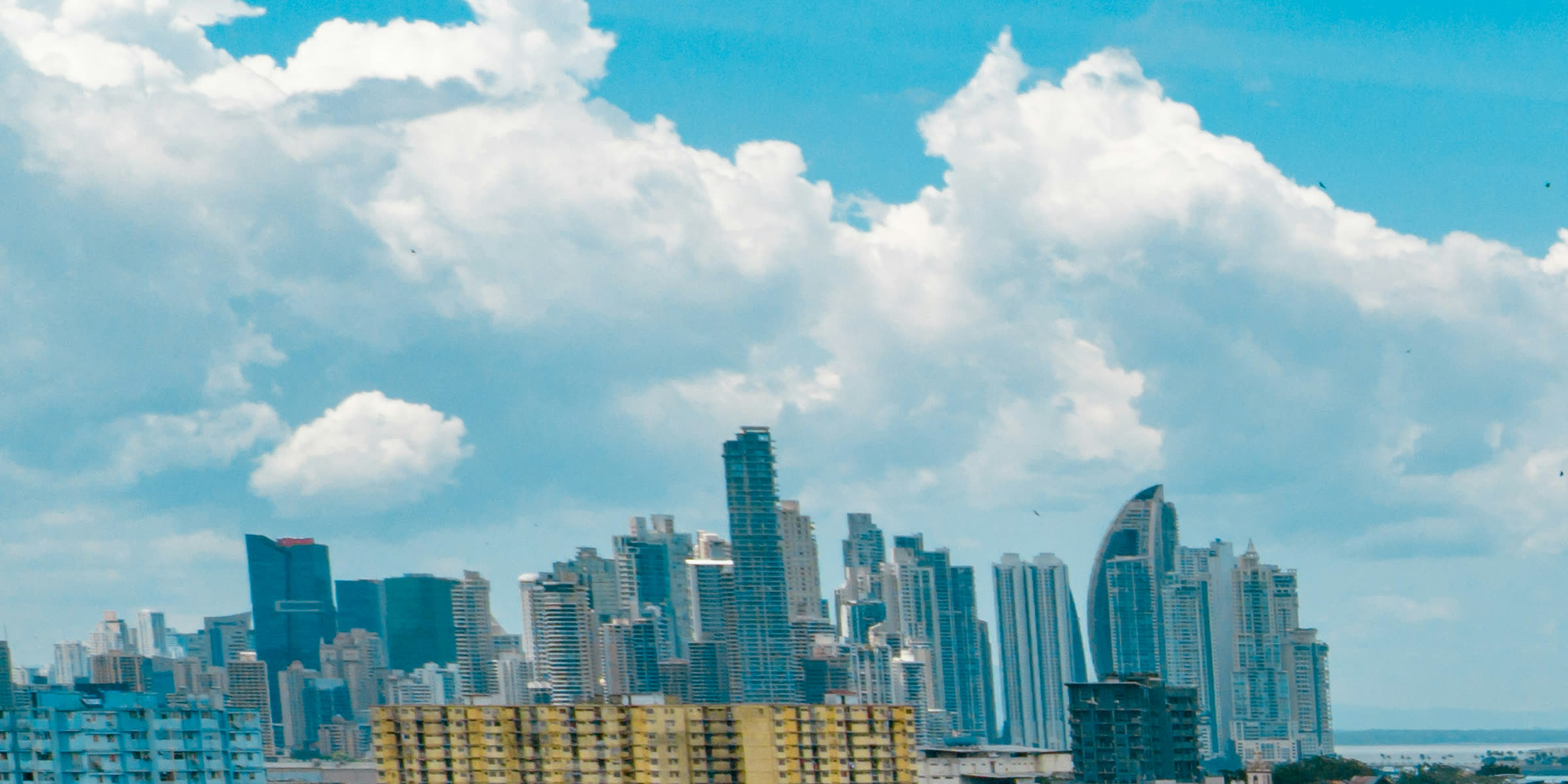 Los rascacielos de la ciudad bajo grandes cúmulos blancos y cielo azul